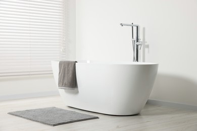 Photo of Stylish bathroom interior with ceramic tub and terry towel