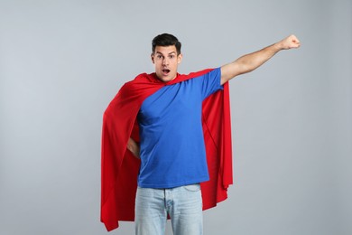 Man wearing superhero cape on grey background