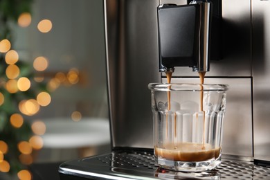 Espresso machine pouring coffee into glass against blurred background, closeup. Space for text