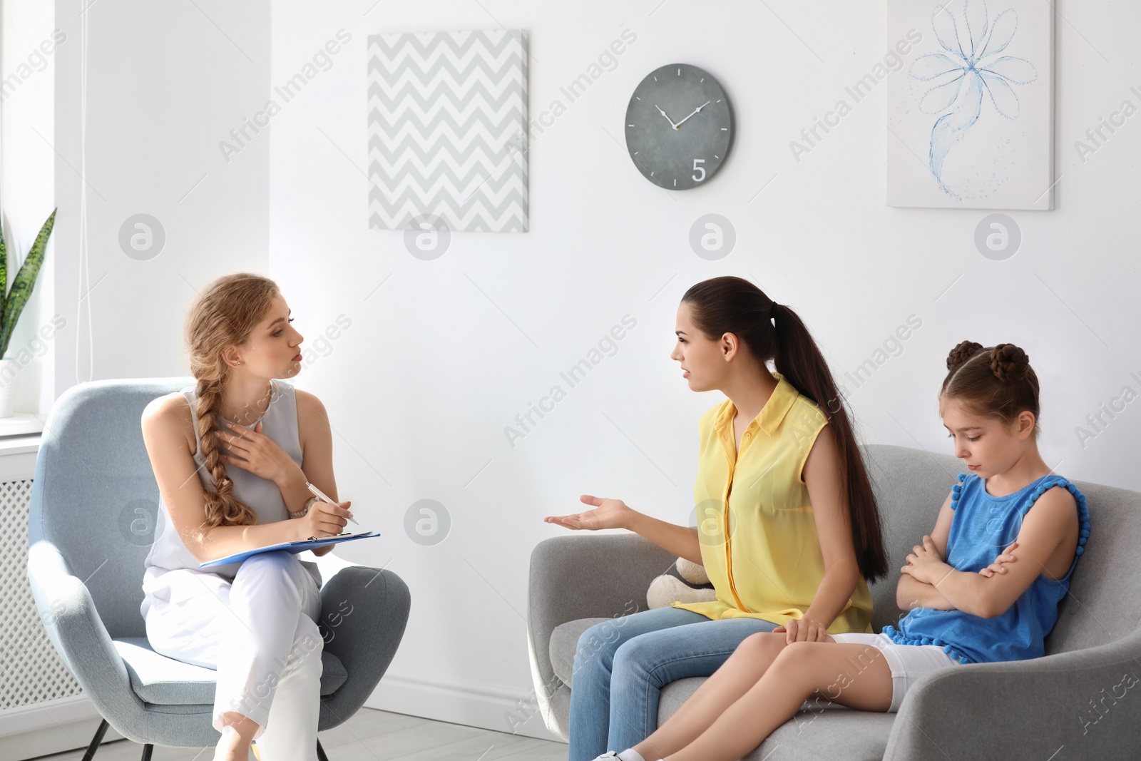 Photo of Young mother and her daughter visiting child psychologist in office