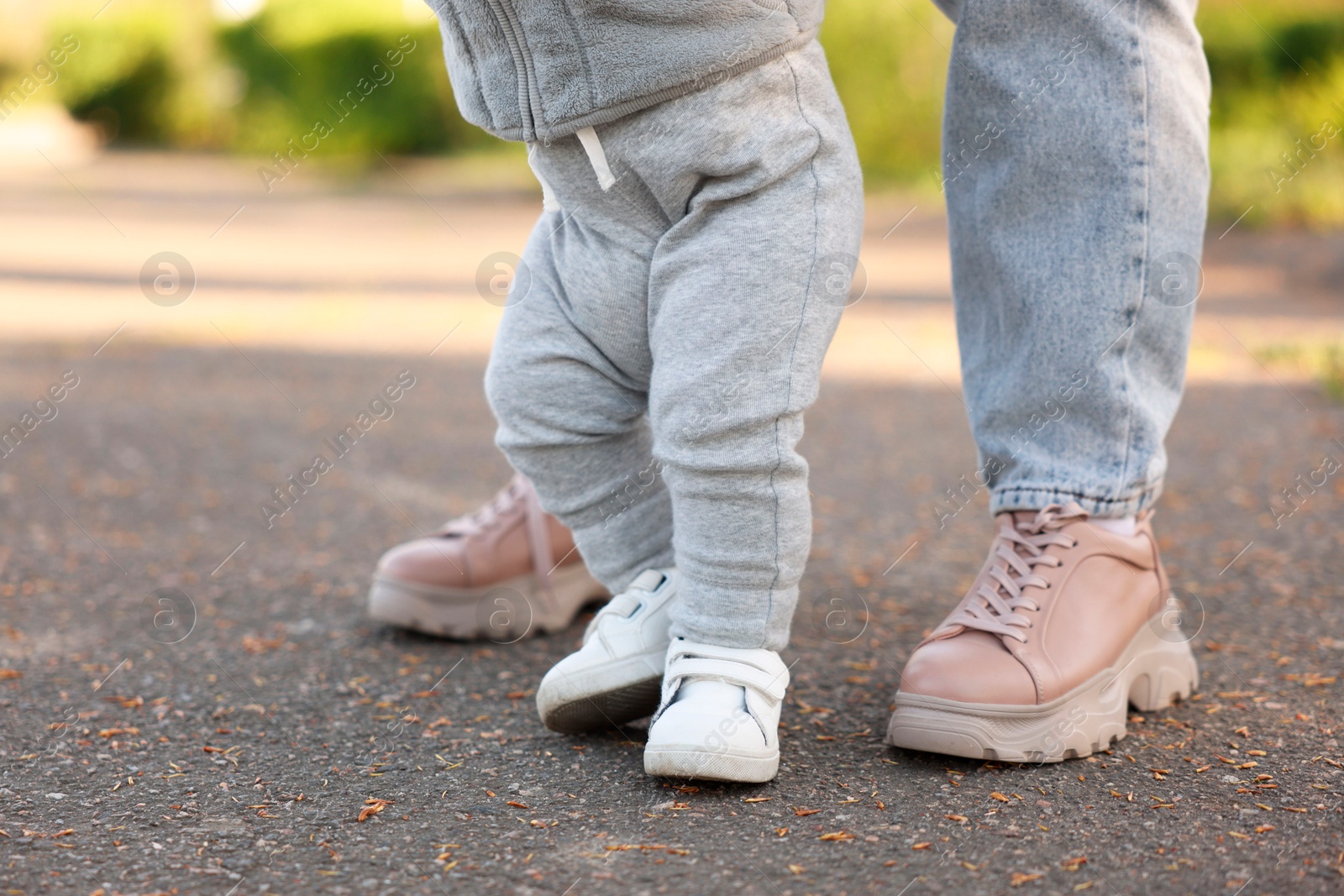 Photo of Mother teaching her baby how to walk outdoors, closeup