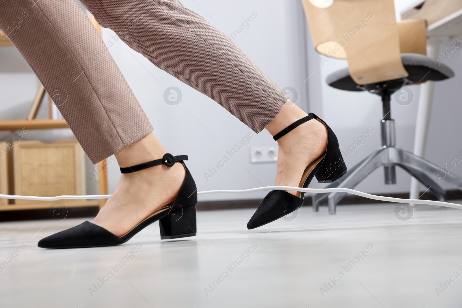 Photo of Woman tripping over cord in office, closeup