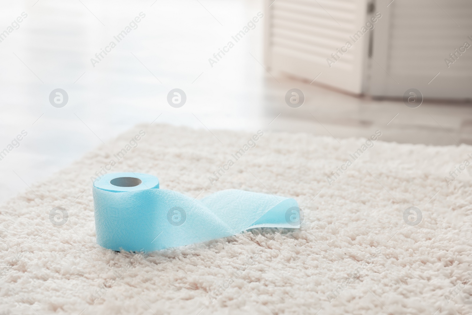 Photo of Toilet paper roll on soft carpet indoors. Space for text