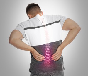Image of Man having backache on light background. Digital compositing with illustration of spine 