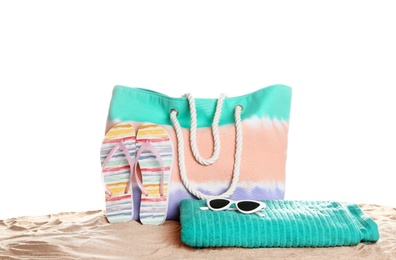 Stylish colorful bag and beach accessories on sand against white background