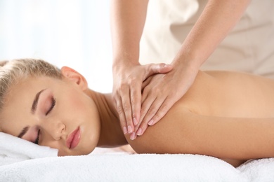 Photo of Relaxed woman receiving shoulders massage in wellness center