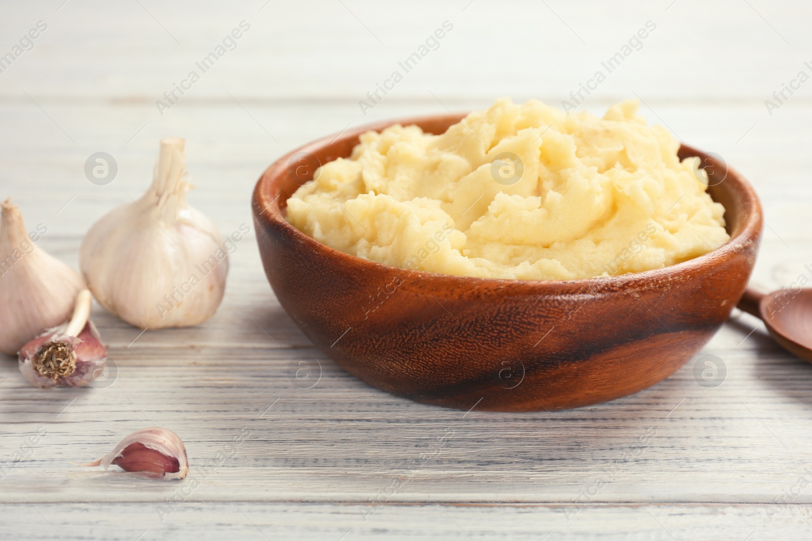 Photo of Bowl with mashed potatoes on wooden table