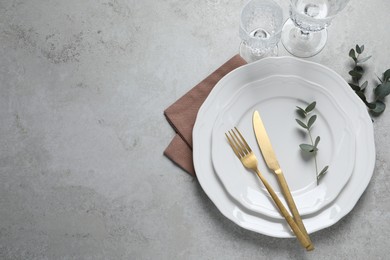 Photo of Stylish setting with cutlery and eucalyptus leaves on light grey table, flat lay. Space for text