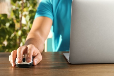 Photo of Man using computer mouse with laptop at table, closeup