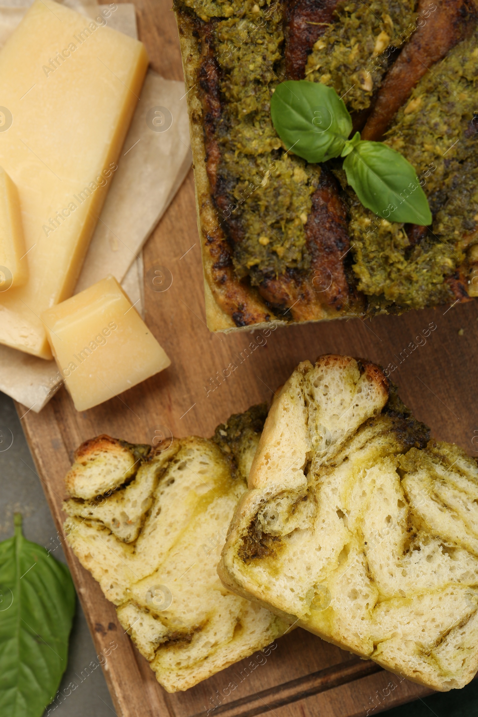 Photo of Freshly baked pesto bread with basil and cheese on grey table, flat lay