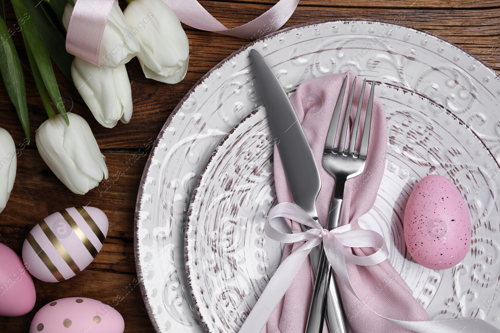 Photo of Festive table setting with painted eggs and tulips, flat lay. Easter celebration