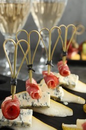 Photo of Tasty canapes with pears, blue cheese and prosciutto on table, closeup