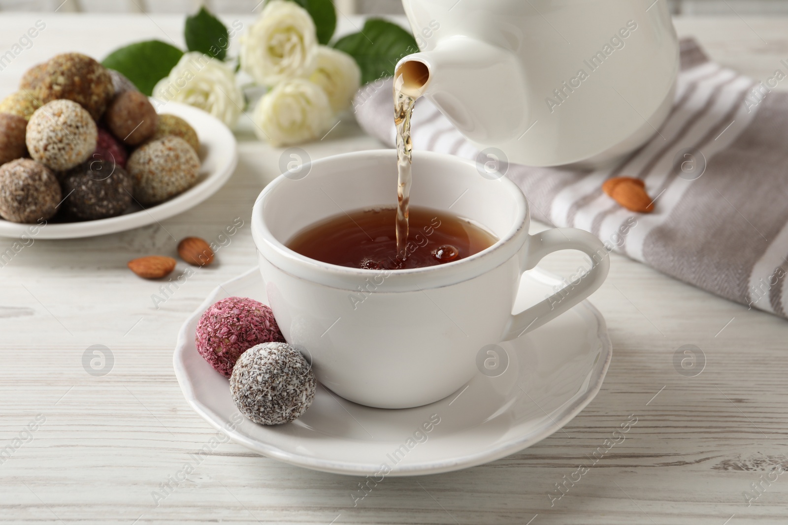 Photo of Pouring tea into cup on white wooden table