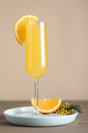 Glass of Mimosa cocktail with garnish on wooden table