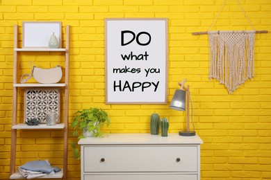 Image of Affirmation. Poster with phrase Do What Makes You Happy on yellow brick wall in room