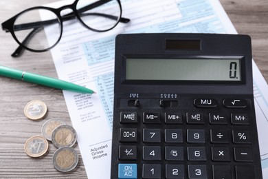 Photo of Tax accounting. Calculator, document, pen and coins on wooden table, closeup