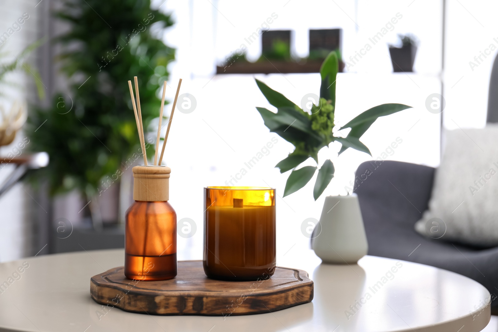 Photo of Reed air freshener and candle on table indoors. Space for text