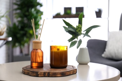 Reed air freshener and candle on table indoors. Space for text