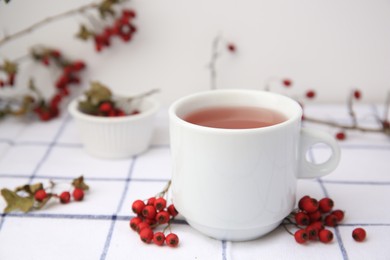 Cup with hawthorn tea and berries on table, closeup. Space for text