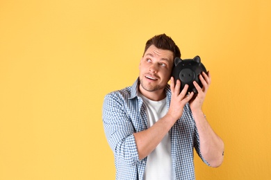 Man with piggy bank on color background