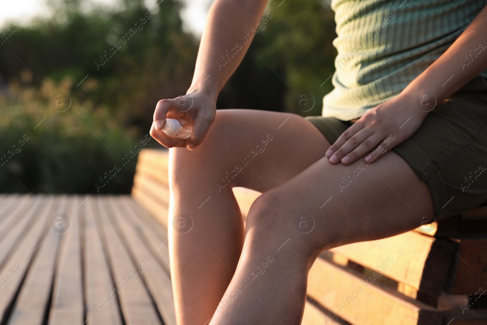 Photo of Woman applying insect repellent onto leg outdoors, closeup