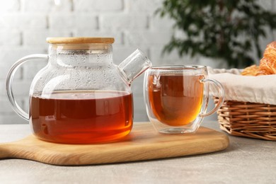 Photo of Aromatic tea in glass cup and teapot on light grey table