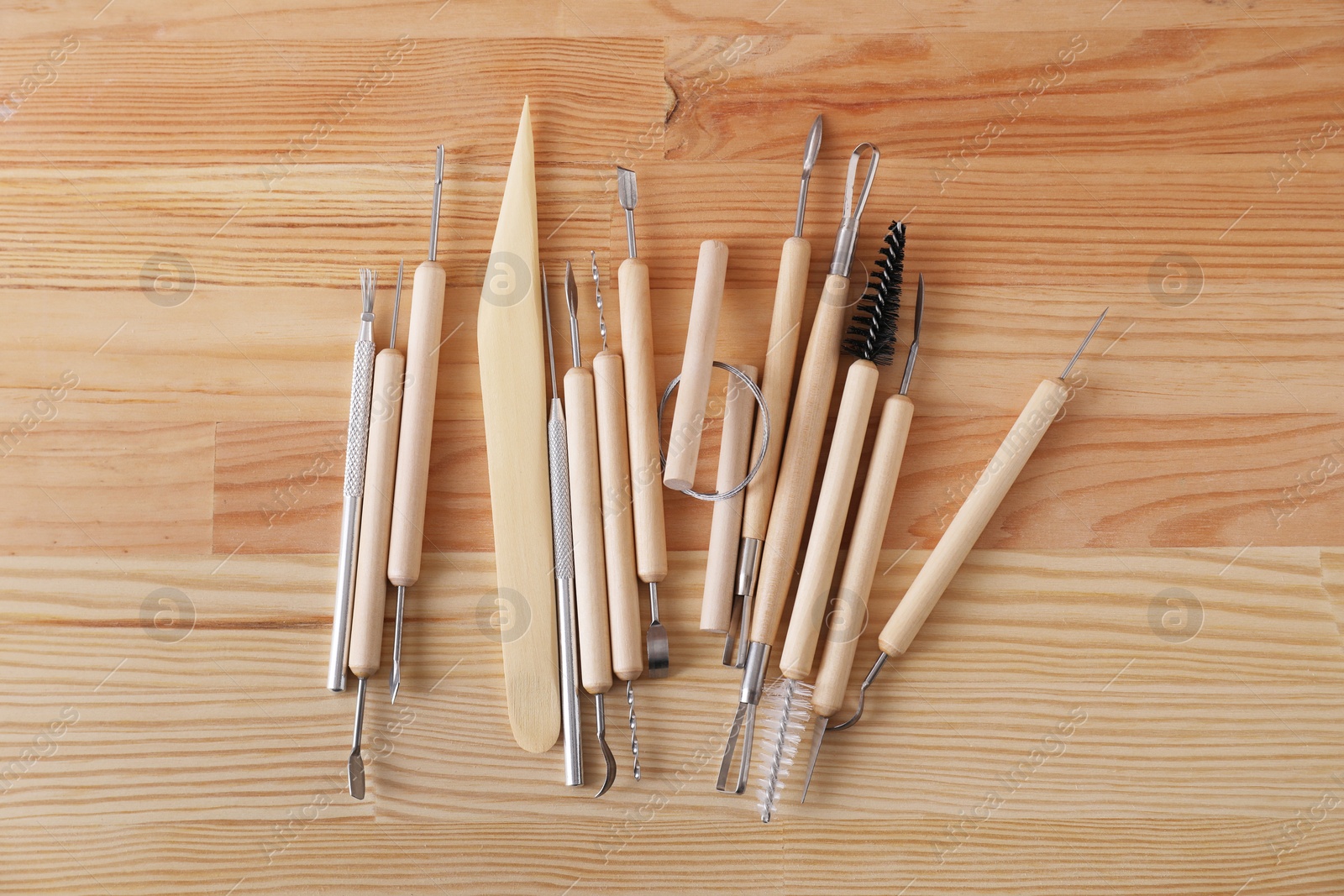 Photo of Set of different clay crafting tools on wooden table in workshop, flat lay