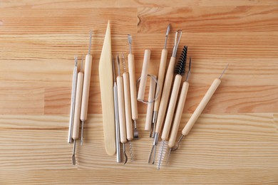 Set of different clay crafting tools on wooden table in workshop, flat lay