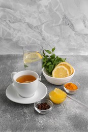 Photo of Cup with delicious immunity boosting tea and ingredients on grey table