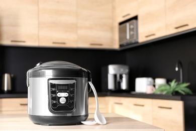 Modern multi cooker on table in kitchen, space for text