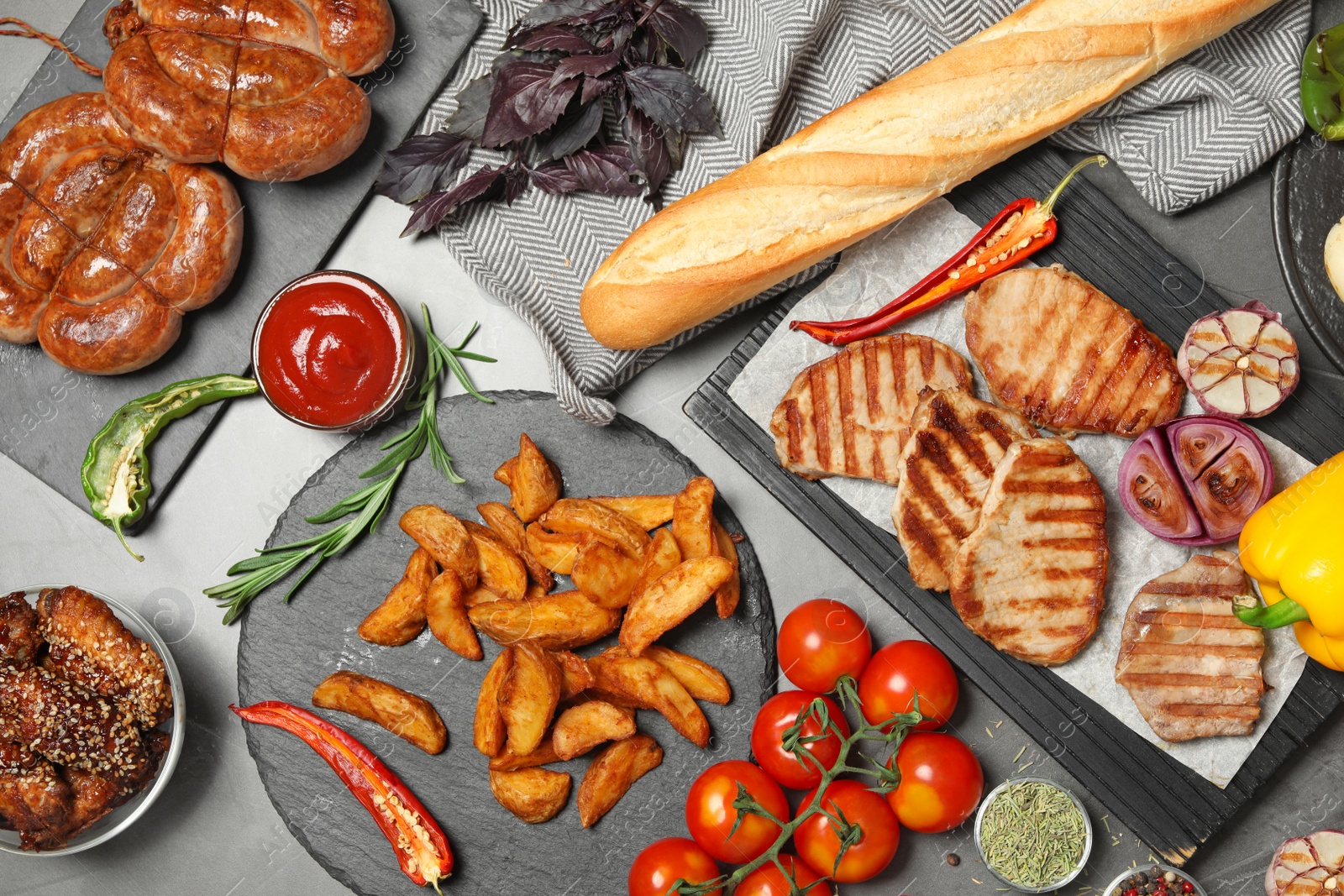 Photo of Flat lay composition with barbecued meat and vegetables on grey table