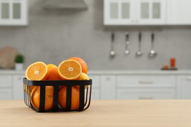 Fresh ripe oranges on wooden table in kitchen, space for text