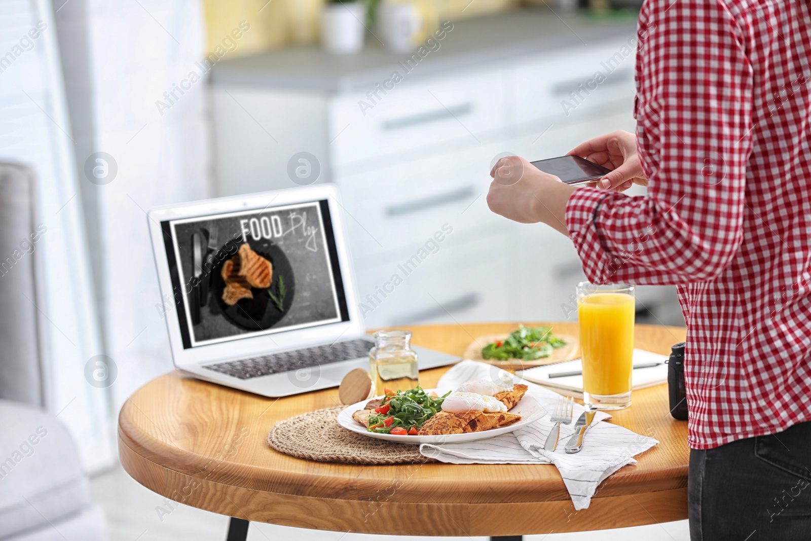 Photo of Food blogger taking photo of her lunch at wooden table indoors, closeup