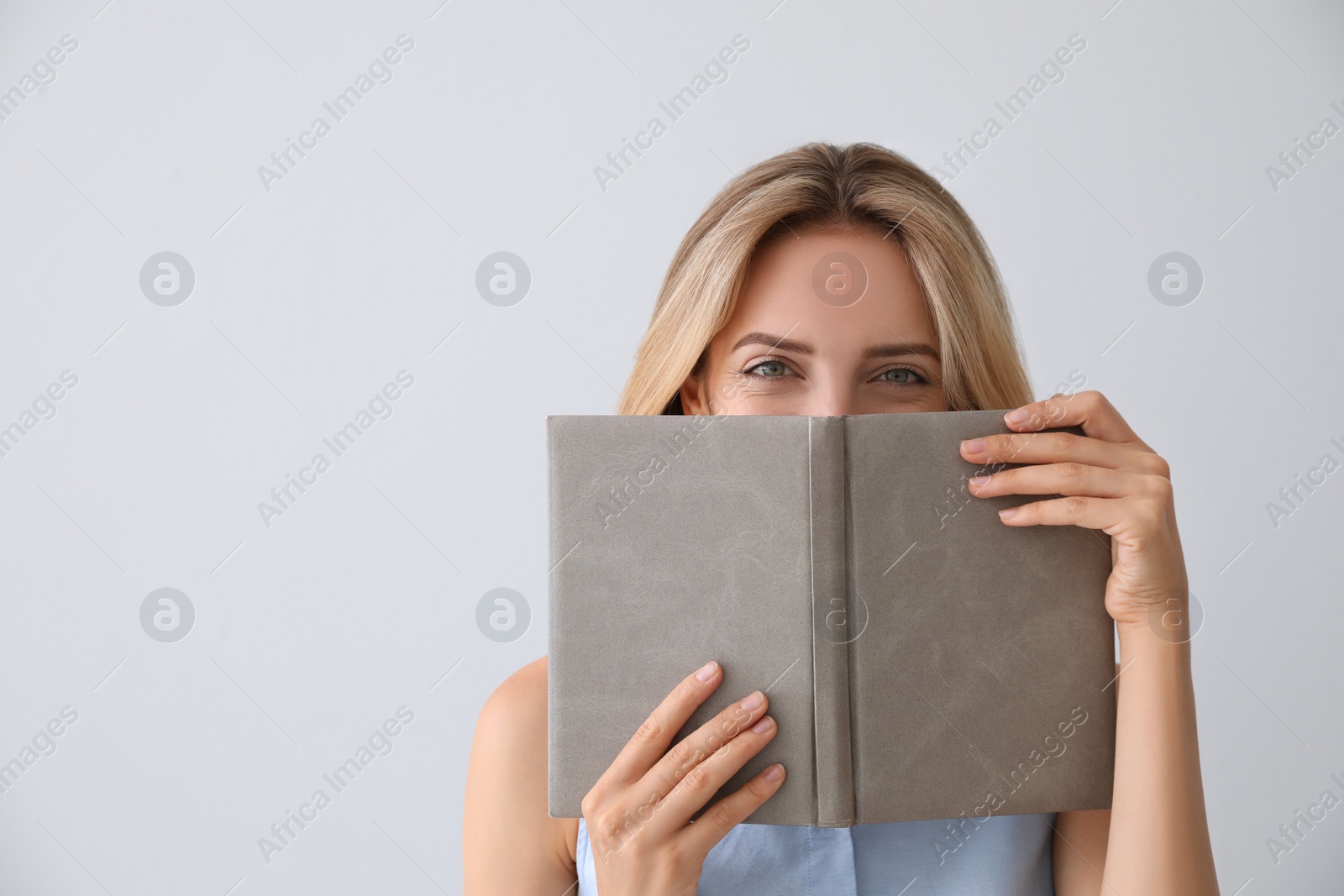 Photo of Beautiful young woman with book on light background. Space for text