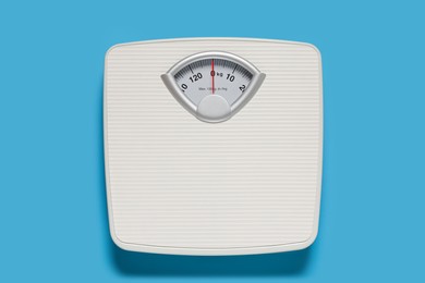 Photo of Bathroom scale on light blue background, top view