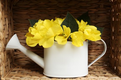Photo of White watering can with beautiful yellow oenothera flowers in wicker box