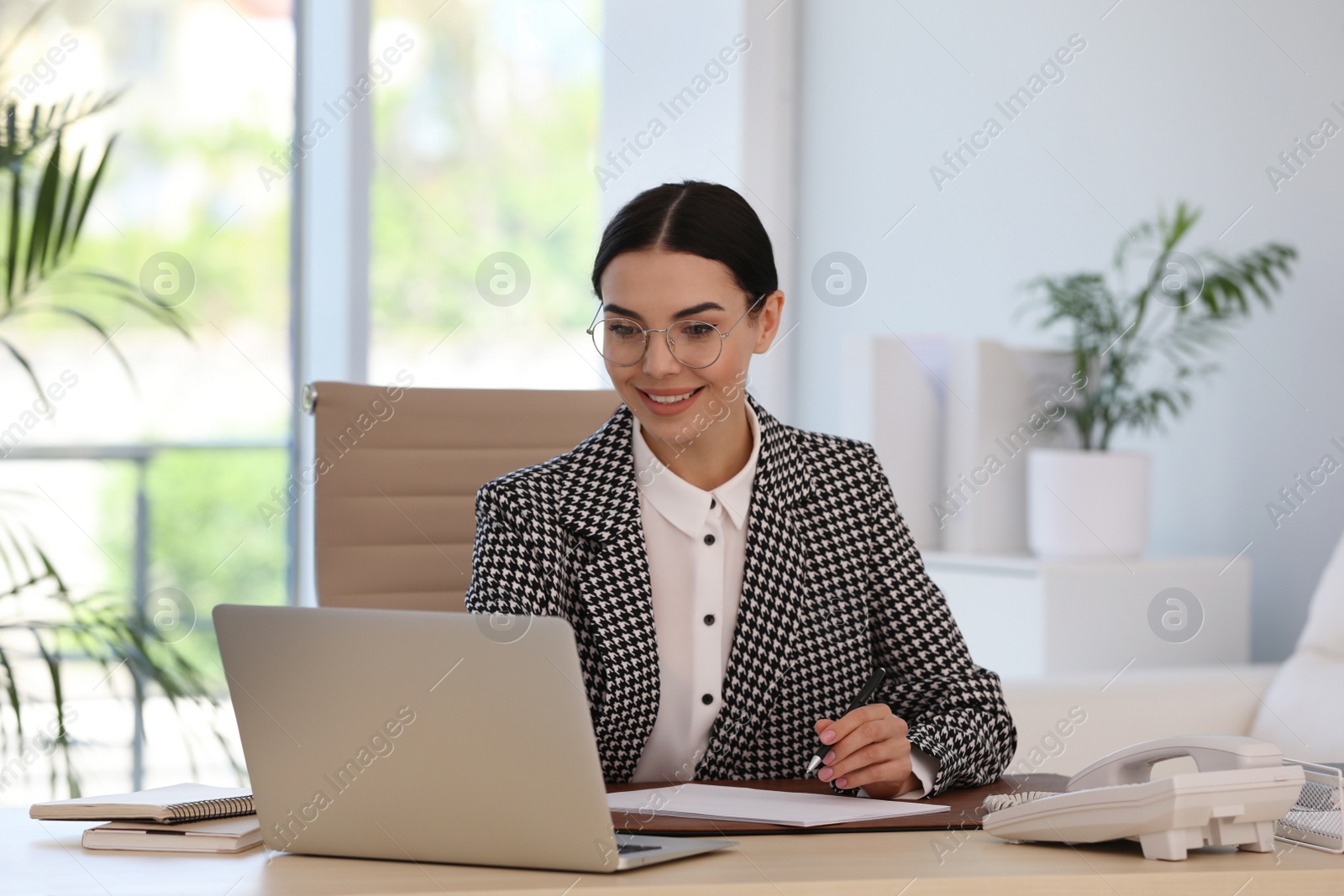 Photo of Secretary working with laptop at wooden table in office