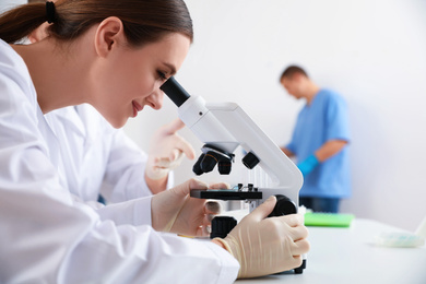 Photo of Scientist with microscope and colleagues in laboratory, closeup. Medical research