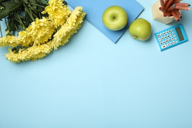 Photo of Flat lay composition with flowers, stationery and apples on light blue background, space for text. Teacher's day