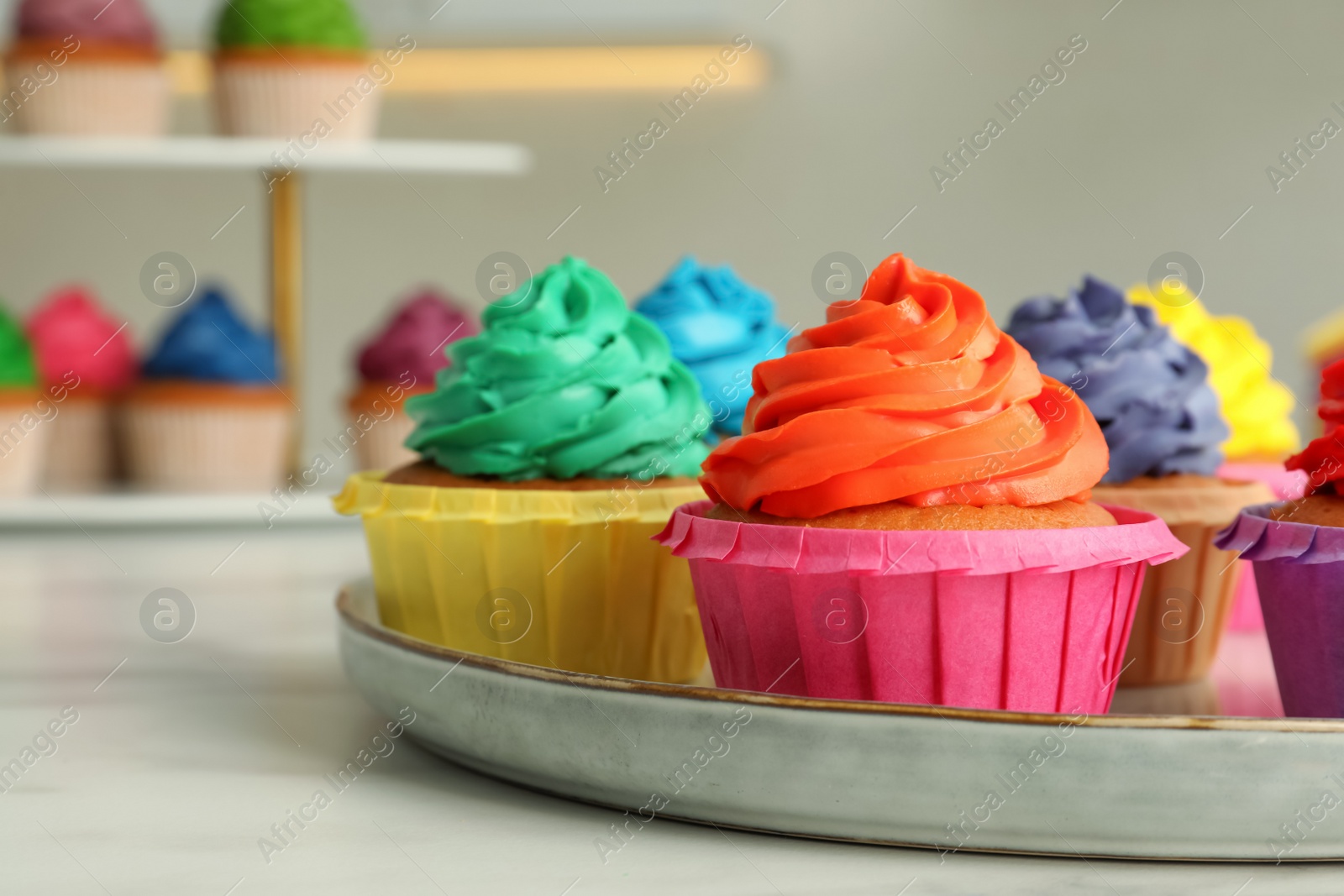 Photo of Delicious cupcakes with colorful cream on white table, closeup