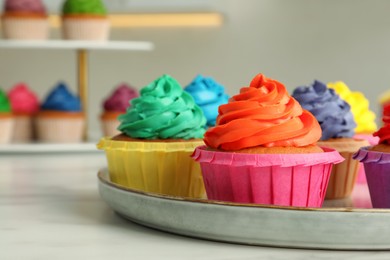 Photo of Delicious cupcakes with colorful cream on white table, closeup