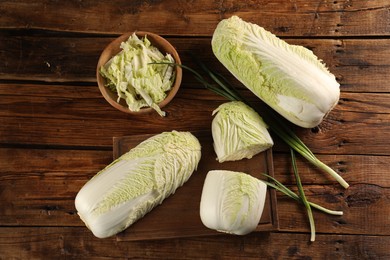 Photo of Fresh ripe Chinese cabbages and green onion on wooden table, flat lay