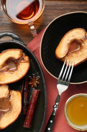 Photo of Tasty baked quinces served with honey and tea on wooden table, flat lay