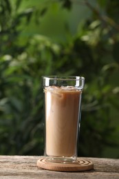 Photo of Glass of iced coffee on wooden table outdoors