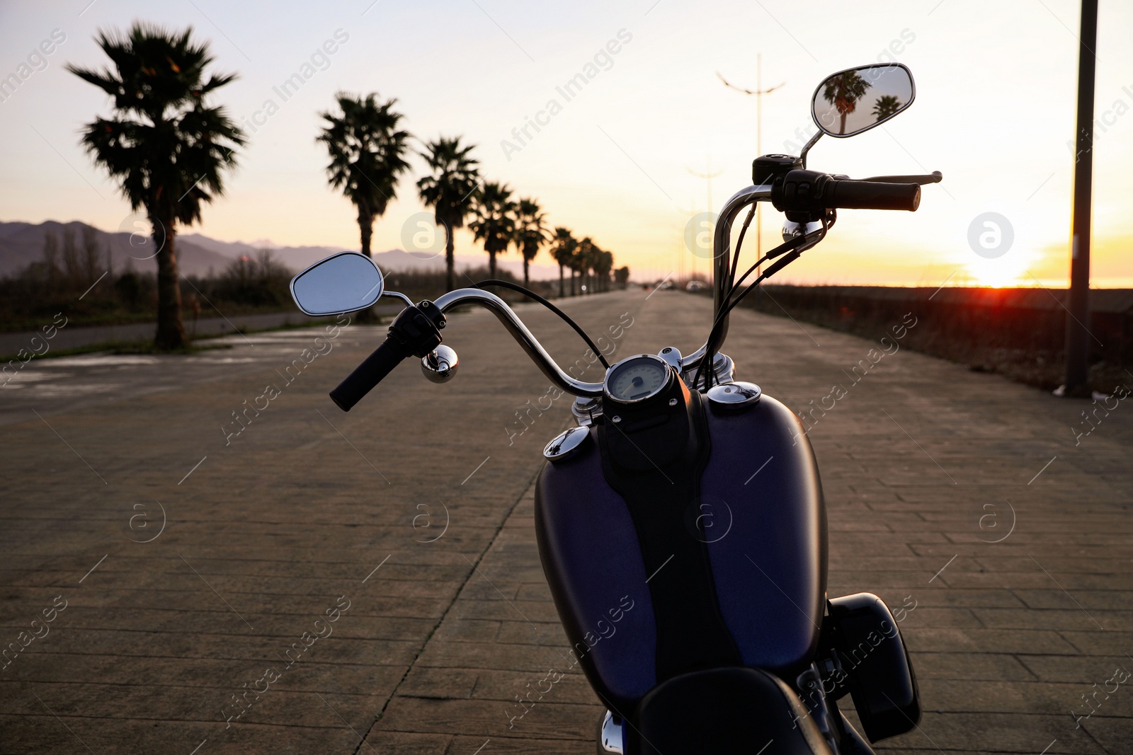 Photo of Modern black motorcycle on road at sunset