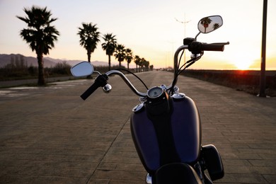 Photo of Modern black motorcycle on road at sunset