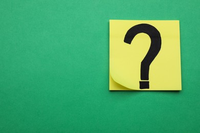 Photo of Sticky note with question mark on green background, top view. Space for text
