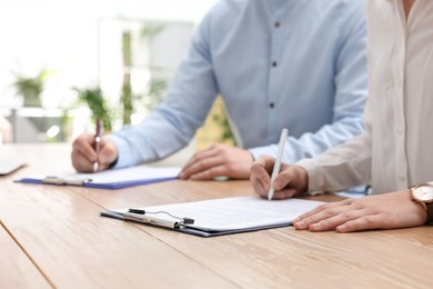 Photo of Woman signing contract at table in office, closeup.