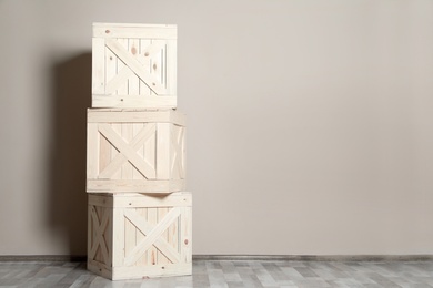 Photo of Wooden crates on floor at beige wall. Space for text