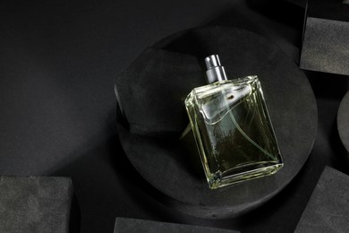 Photo of Stylish presentation of luxury men`s perfume in bottle on black background, above view. Space for text